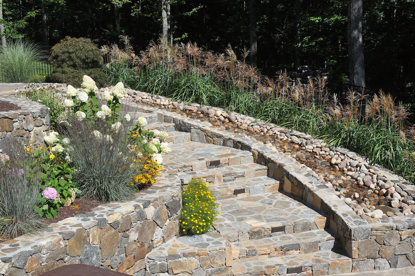 Decorative water feature with masonry and planting integrated into the landscape